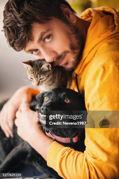 man cuddling with his cat and his dog - dog and cat sitting stock pictures, royalty-free photos & images