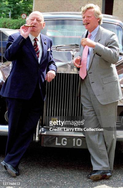 British media mogul Lew Grade with his nephew Michael Grade , smoking cigars by a Rolls Royce, circa 1985. The car's numberplate reads 'LG10'.