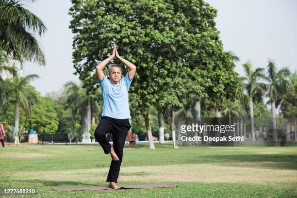 senior man in public park - on one leg stock pictures, royalty-free photos & images