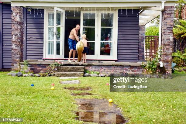 father and child outside house in the christmas season - new zealand christmas stock pictures, royalty-free photos & images