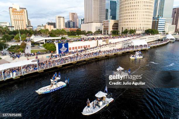 Boat carrying Ondrej Palat, Jan Rutta, and Erik Cernak cruises by fans watching at Curtis Hixon Park on the Hillsborough River at the Tampa Bay...