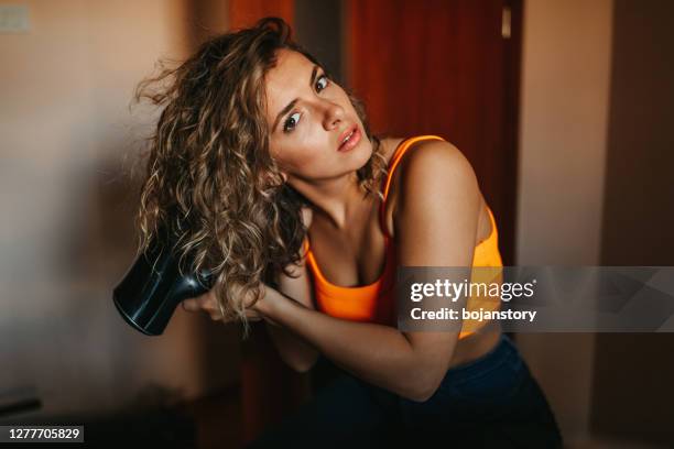 young woman dries her hair with hairdryer - drying hair stock pictures, royalty-free photos & images