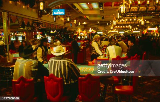 Nevada, Las Vegas, Customers and croupiers at gambling tables in the Luxor Hotel.