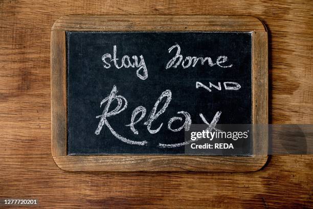 Stay home quarantine isolation period concept. Vintage chalkboard with handwritten chalk lettering Stay home and relax. Wooden background.