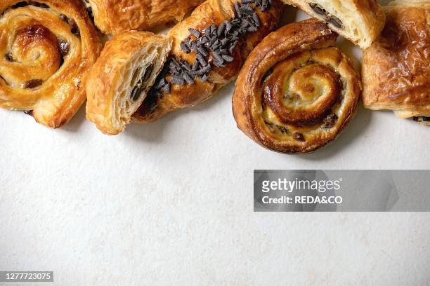 Variety of traditional french puff pastry buns with rasin and chocolate. Croissant over white texture background. Flat lay. Space.