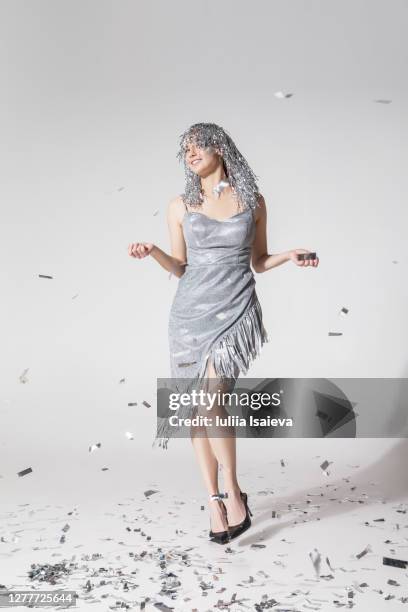 cheerful woman walking under falling confetti - zilverkleurige jurk stockfoto's en -beelden