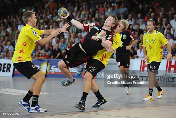 Frank Loke of Luebbecke is challenged by Michael Quist and Vladica Stojanovic of Hildesheim during the Toyota Handball Bundesliga match between TuS...