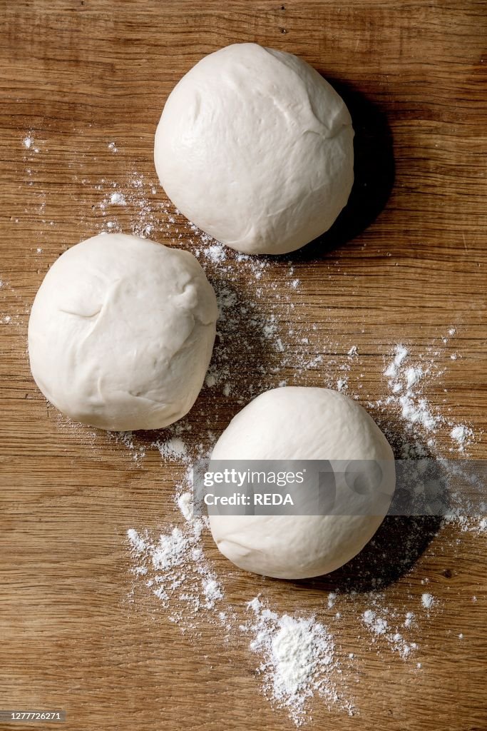 Dough for pizza cooking. Three balls of fresh homemade wheat dough on wooden table. Home baking. Flat lay, space