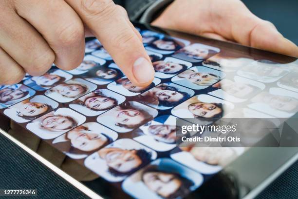 finger selecting profile picture on tablet mobile device - stalker foto e immagini stock