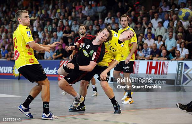 Frank Loke of Luebbecke is challenged by Michael Quist and Vladica Stojanovic of Hildesheim during the Toyota Handball Bundesliga match between TuS...