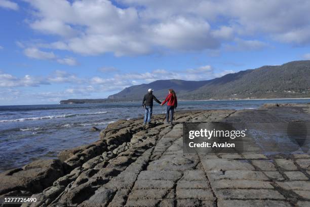 Young couple walking over the Tessellated Pavement in Tasman Peninsula Tasmania Australia.