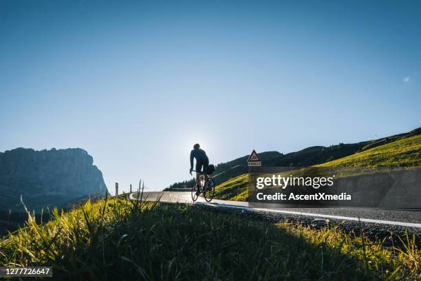 road biker ascends mountain road in the morning - cross country road trip stock pictures, royalty-free photos & images