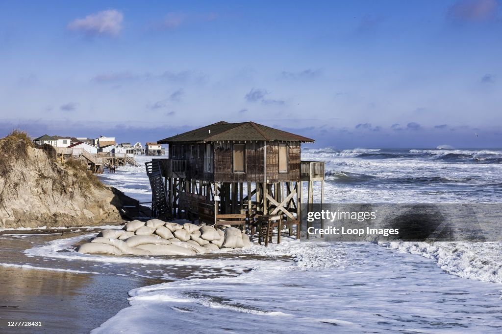 Nags Head beach house on stilts surrounded by high tide storm surf.