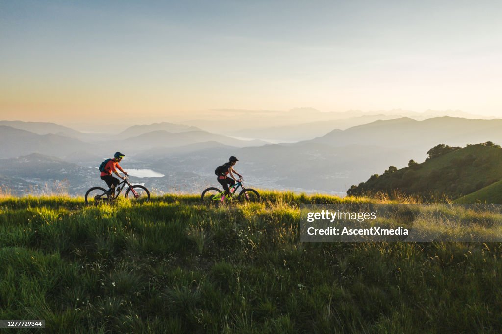 Mountain bikers ride along grassy mountain ridge