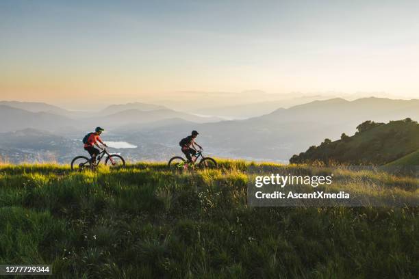 mountain bikers ride along grassy mountain ridge - ticino canton stock pictures, royalty-free photos & images