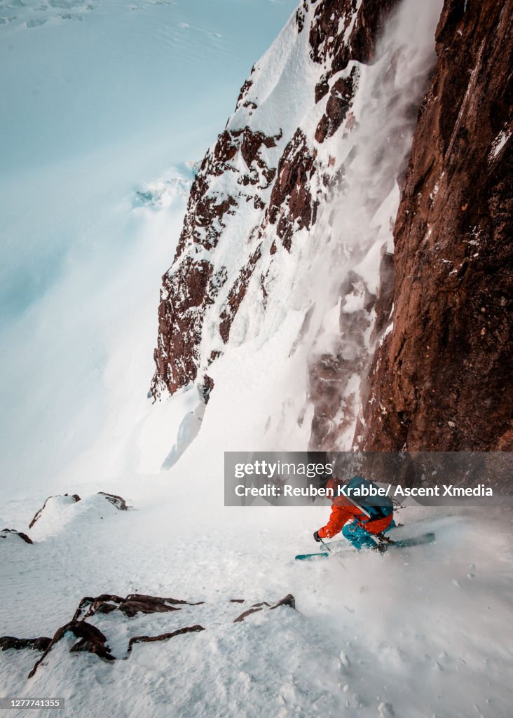 Backcountry skier descends steep snow couloir