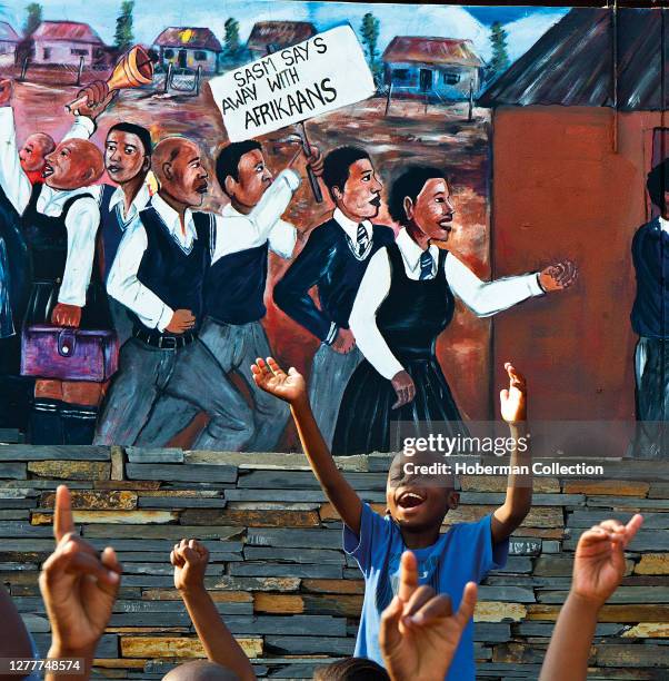 African boy in front of mural protesting Soweto riots, Johannesburg, South Africa