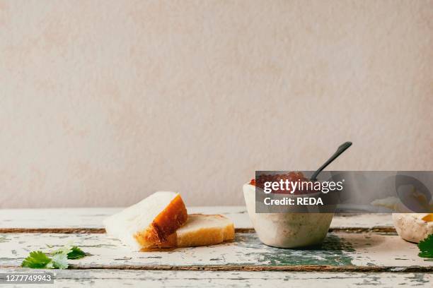 Red salmon caviar in ceramic bowl. Server with sliced wheat bread and butter on old wooden table. Rustic style. Copy space.