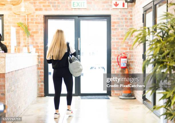 full length teenager leaving reception with glass doors - gym reopening stock pictures, royalty-free photos & images