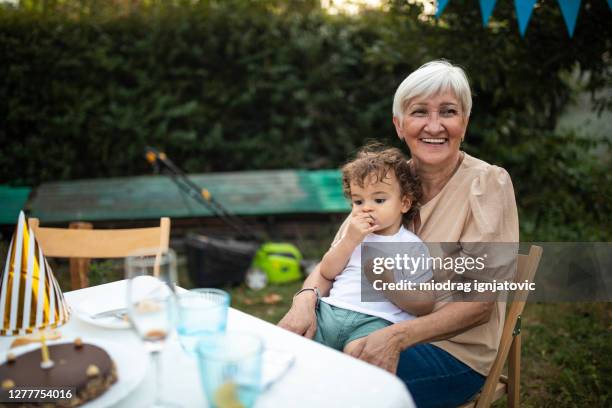 裏庭での誕生日パーティー中にダイニングテーブルに座っている祖母と孫 - grandma birthday ストックフォトと画像