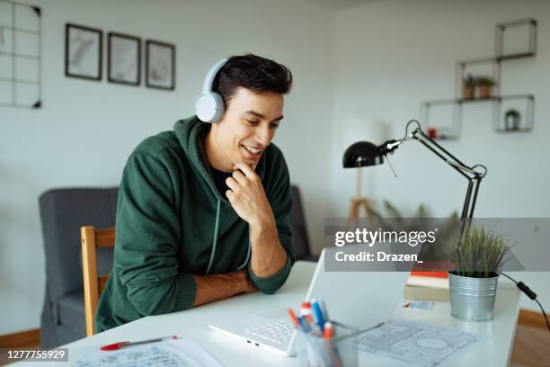 trabajando y estudiando desde casa. vlogger delante de la computadora portátil - hombre joven fotografías e imágenes de stock