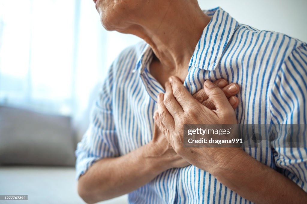 Senior Woman Suffering From Chest Pain While Sitting on Sofa at Home.