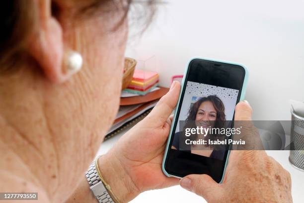 close-up of senior woman video chatting with family - mother daughter webcam stockfoto's en -beelden