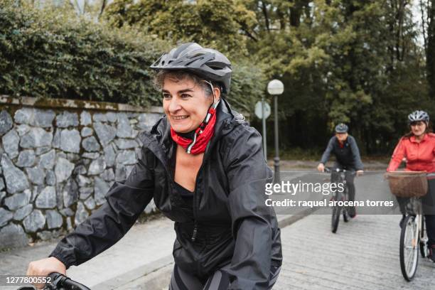 group of mature people riding bikes with helmet and casual sportswear - familie fietsen close up stockfoto's en -beelden