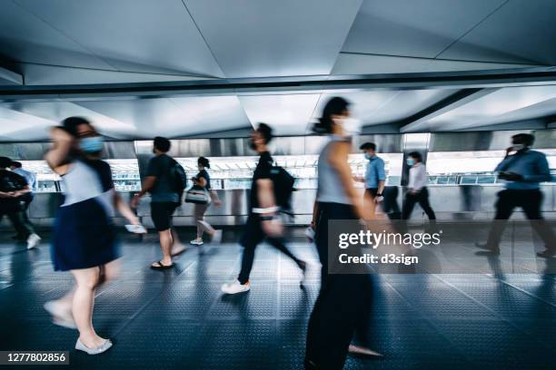 blurred motion of busy commuters with protective face mask walking on urban bridge in downtown district during rush hours in the city - hong kong mass transit fotografías e imágenes de stock