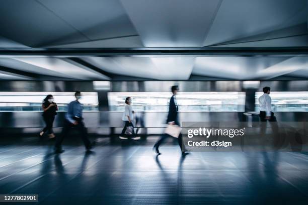 blurred motion of busy commuters with protective face mask walking on urban bridge in downtown district during rush hours in the city - hong kong mass transit fotografías e imágenes de stock