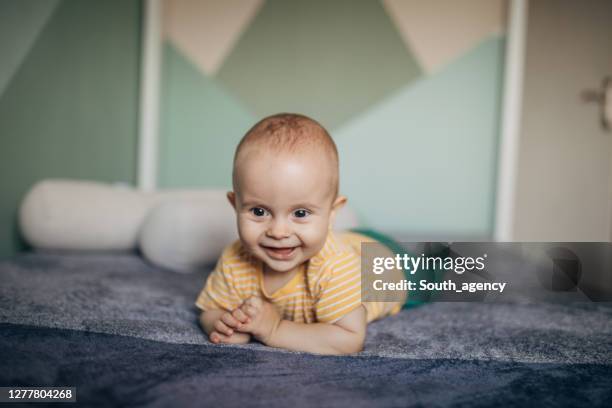 adorable smiling baby boy lying down on the bed - boy lying down stock pictures, royalty-free photos & images