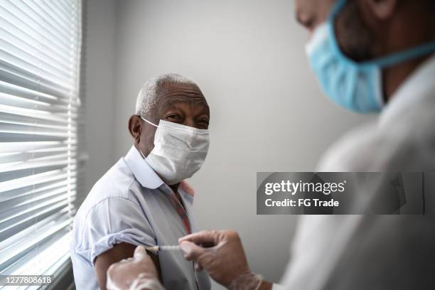 nurse applying vaccine on patient's arm using face mask - safe injecting stock pictures, royalty-free photos & images