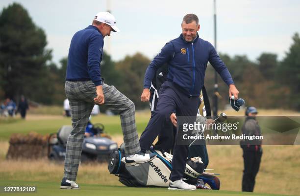Ian Poulter and Lee Westwood of England do a foot tap as a socially distanced acknowledgement after their first round of the Aberdeen Standard...