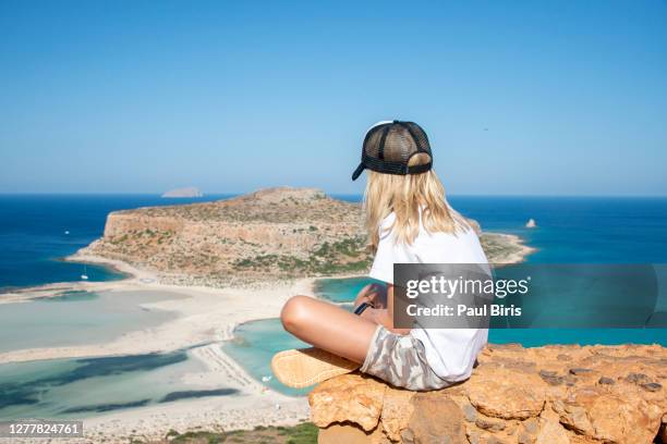 young little boy relaxing on a rock against a blue sea , balos beach, crete, greece - balonnen stock-fotos und bilder