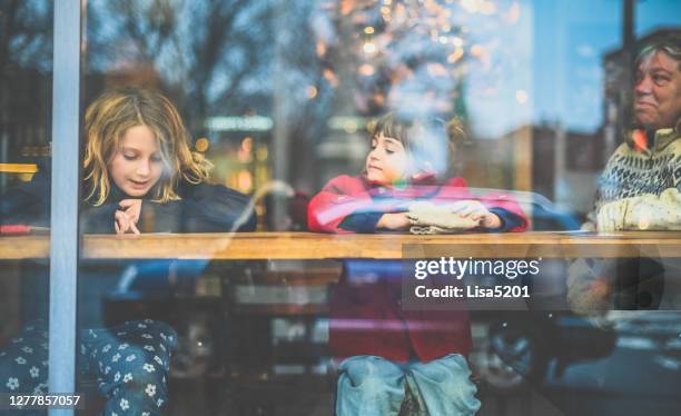 two children with senior woman at a urban cafe in winter - child behind bars stock pictures, royalty-free photos & images