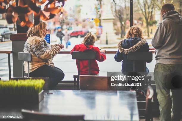 two children with father and grandmother at a urban cafe in winter - child behind bars stock pictures, royalty-free photos & images