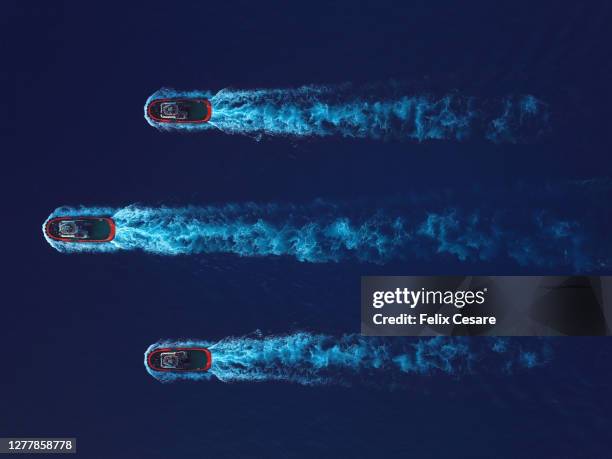 aerial top view of three tugboat on the move surrounded by deep blue water. - remolcador fotografías e imágenes de stock