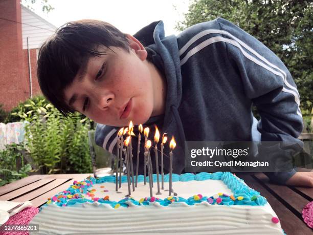 twelve-year-old boy blowing out his birthday cake candles - 13 year old cute boys stock pictures, royalty-free photos & images