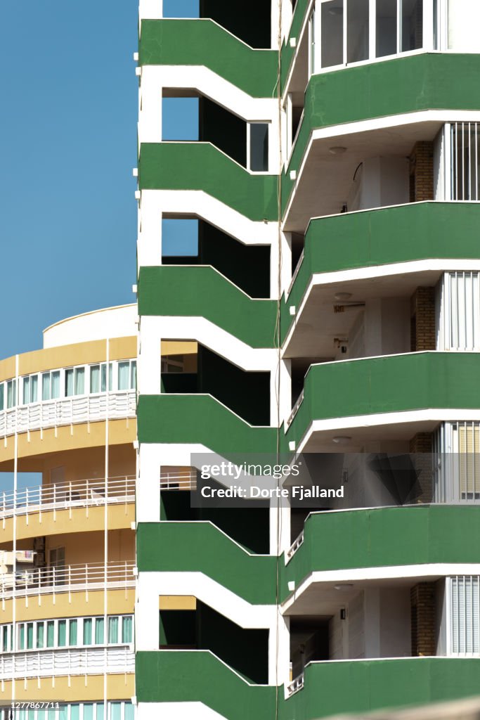 Details of a green building with a yellow building and blue sky in the background