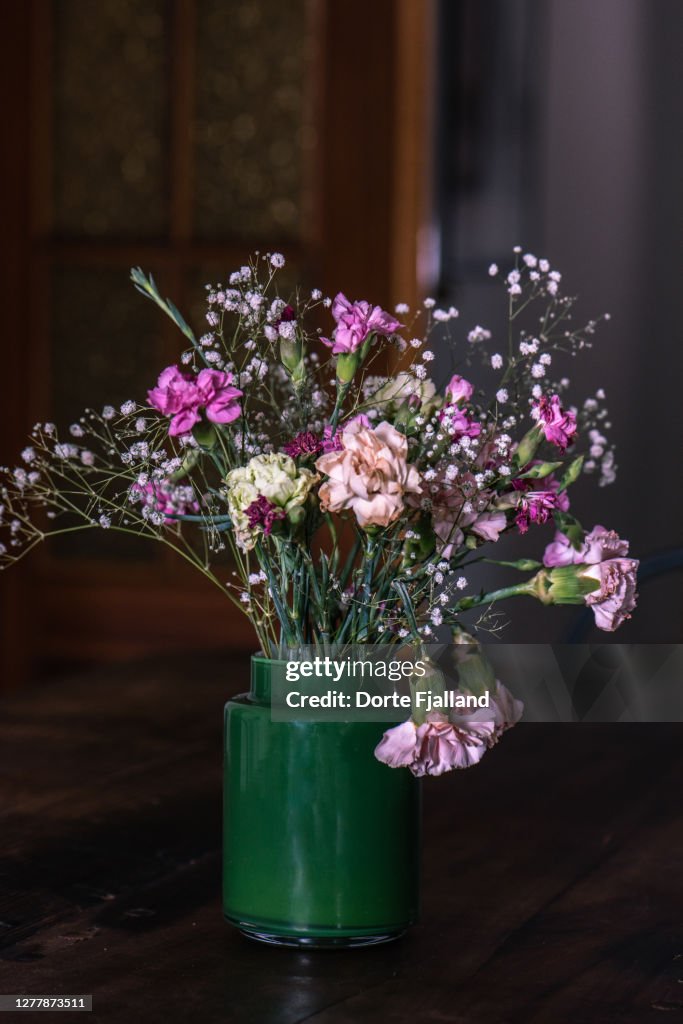 A bouquet of gypsophilias and pink carnations against a dark background