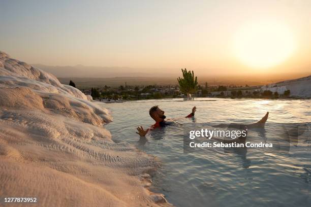 young attractive man having fun in travertines pools and terraces, pamukkale, hierapolis, golden hour in turkey at sunset time. - pamukkale stock pictures, royalty-free photos & images