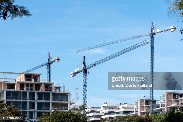 three tall cranes and buildings under construction - built structure fotografías e imágenes de stock