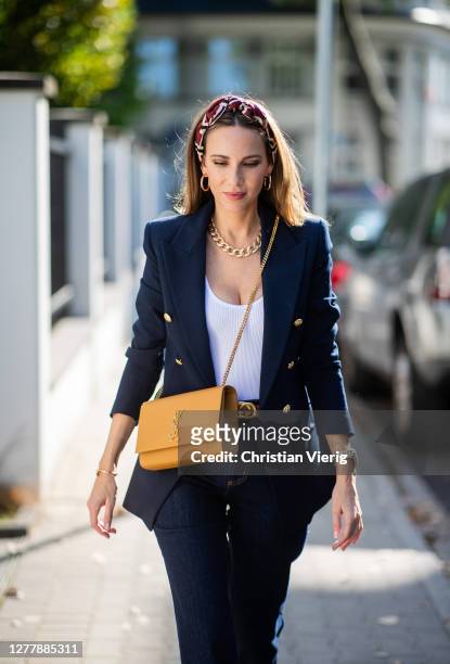Alexandra Lapp is seen wearing SAINT LAURENT Kate medium bag in camel, Ariane Ernst hoop earrings in gold, white body and dark blue blazer with...