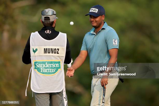 Sebastian Munoz of Colombia tosses the ball to his caddie Mateo Gomez after making birdie on the 16th green during the first round of the Sanderson...