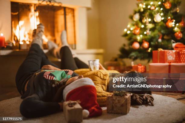 two females are laying down next to the fireplace relaxing and warming their feet - hot latin nights stock pictures, royalty-free photos & images