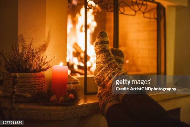 schönes foto von einem füße in weihnachten socken erwärmung auf dem kamin - kaminfeuer stock-fotos und bilder