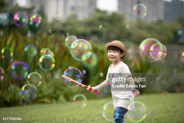 asian chinese young girl blowing bubbles at public park enjoying playing - catching bubbles stock pictures, royalty-free photos & images