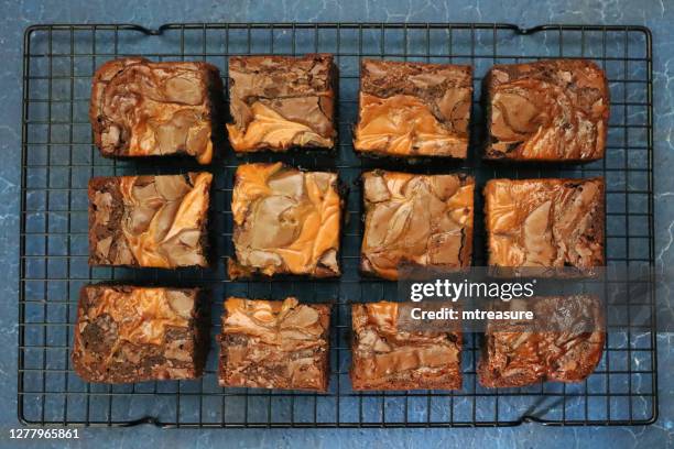 image of homemade chocolate salted caramel brownie squares on metal cooling rack, grey slate background, elevated view - salted brownie stock pictures, royalty-free photos & images