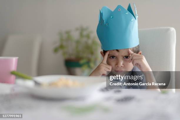 child with foam crown eats macaroons at home. king of home. - king stock pictures, royalty-free photos & images
