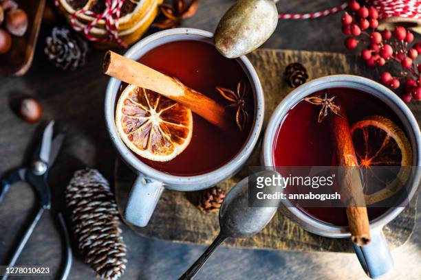 cups of mulled wine with cinnamon and orange on a chopping board - ホットワイン ストックフォトと画像